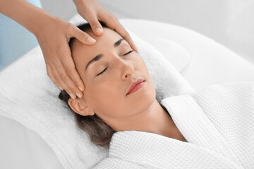 Fototapeta na wymiar Beautiful mature woman receiving face massage in spa salon