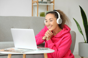 Mature woman with laptop and headphones at home