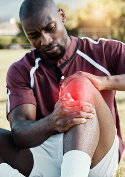 Injury, soccer player and athlete with pain on knee on a sports field, hurt and inflammation on his leg during a match. Black man, sportsman and person playing football with red overlay in fitness