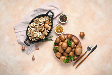 Plate and baking dish of fresh mushrooms with different spices on pink background