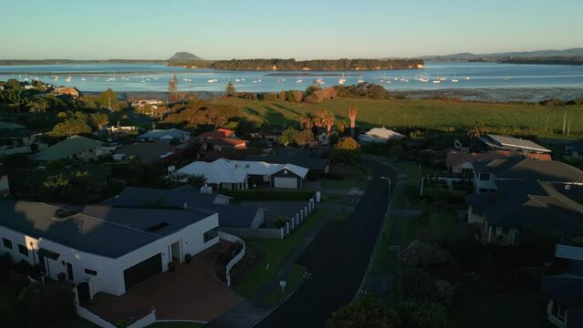 Sunset aerial view of coastal neighborhood in Akaroa, New Zealand, overlooking Mount Manganui