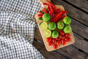Photograph of tomatoes, lemons, and chilies placed on wood