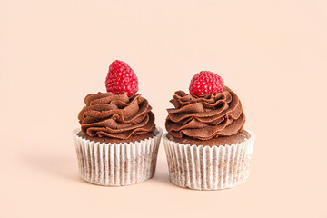 Tasty chocolate cupcakes with raspberries on beige background