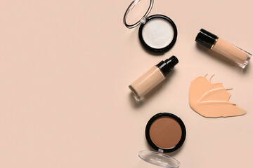 Bottles of makeup foundation with sample and cosmetic products on beige background