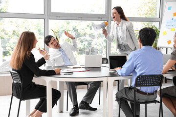 Young businesswoman with megaphone shouting at colleagues in office
