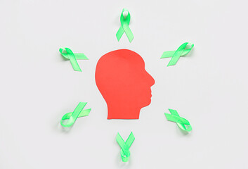Paper human head with green awareness ribbons on grey background. Mental Health Day