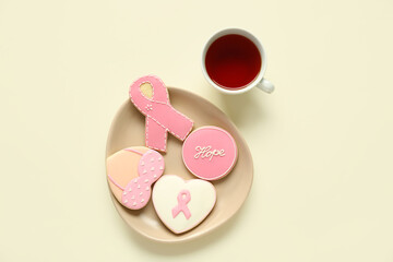 Plate with pink cookies and cup of tea on light background. Breast cancer awareness concept