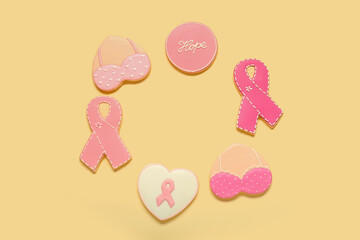 Circle made of different pink cookies on yellow background. Breast cancer awareness concept