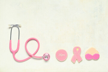 Pink cookies and stethoscope on light background. Breast cancer awareness concept