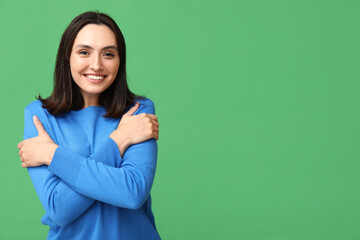 Young woman hugging herself on green background