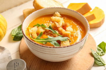 Bowl of delicious pumpkin cream soup with arugula and croutons on white background - obrazy, fototapety, plakaty