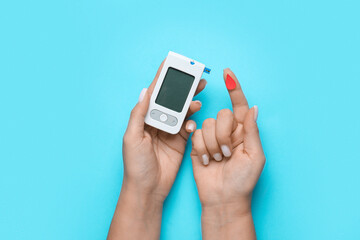 Woman with glucometer and paper blood drop on blue background. Diabetes concept