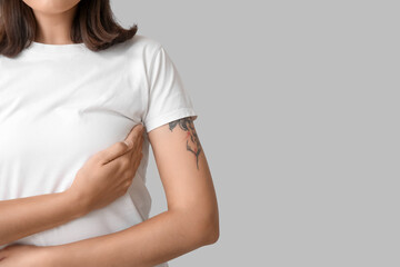Obraz premium Young woman checking her breast on light background, closeup. Cancer awareness concept