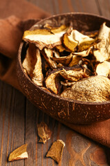 Bowl with tasty dried mushrooms on wooden background, closeup