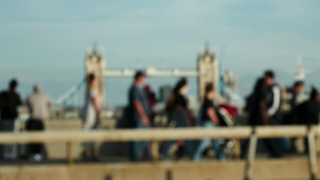 Pendler &uuml;berqueren die London Bridge an einem sonnigen Nachmittag im Herbst, im Hintergrund die Tower Bridge in Unsch&auml;rfe.