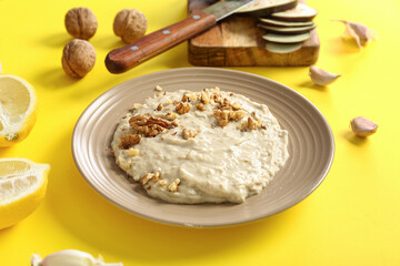 Plate of tasty baba ghanoush on yellow background