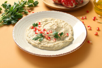 Plate of tasty baba ghanoush on orange background