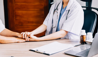 Doctor giving hope. Close up shot of young female physician leaning forward to smiling elderly lady patient holding her hand in palms. Woman caretaker in white coat supporting encouraging old person