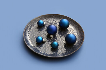Plate with Christmas balls on blue background