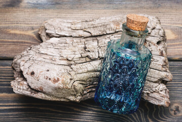 Herbal medicine concept background. Remedy bottle with blue liquid on the wooden table background....