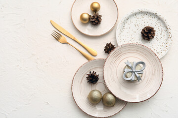 Beautiful table setting with Christmas balls, cones and gift box on white background