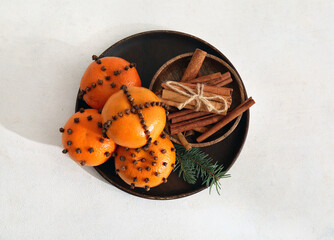 Wooden plate with pomander balls and cinnamon on white background