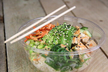 Poke Bowl Chopsticks Avocado Chicken Sesame Tofu, Edamame Food Wood background 