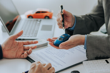 Close up of Asian man's car insurance document or rental agreement or agreement Trading with car keys on the table Making a contract for buying or renting a car