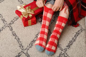 Woman in warm socks at home with Christmas gift boxes