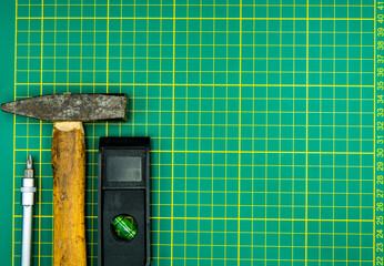 screwdriver hammer and spirit level isolated on green cutting mat