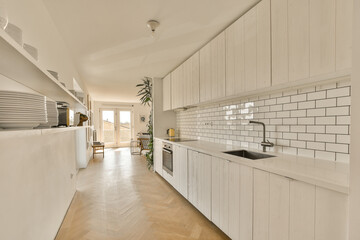 a kitchen with white cabinets and wood flooring in the center of the image is an open door leading...
