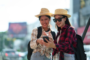Two young Asian female tourists shopping, holding shopping bags and walking happily, enjoying...