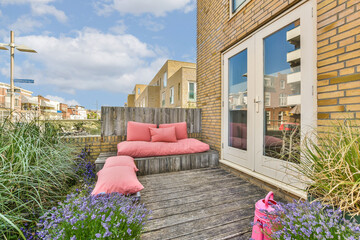 an outside area with some plants and flowers on the deck, including pink pillows and purple flowers...