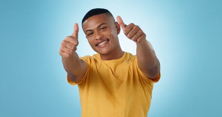 Thumbs up, portrait and man in studio for success, winning deal and celebrate achievement on blue...