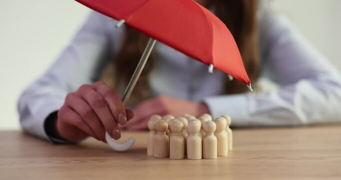 Group of wooden dolls hides under red umbrella