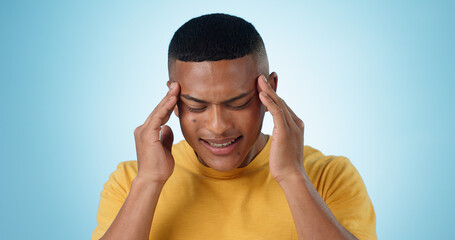 Man, pain and headache in studio of stress, challenge or fatigue of mental health on blue...
