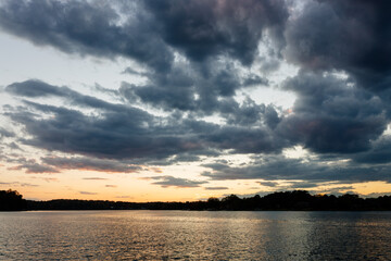 Beautiful sky over the lake at sunset in autumn. Autumn scenic landscape with river and orange sunrise clouds