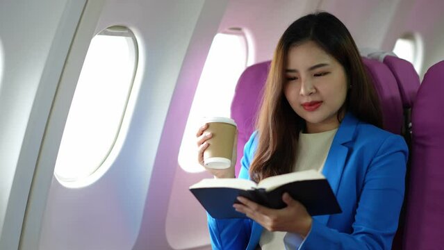 Asian businesswoman reading a book in an airplane business travel online communication Gain business knowledge and relax work lifestyle concepts.