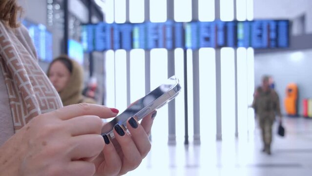 Close-up. People in international airport. Female traveler look at phone, search for boarding pass or flight cancelation information. 4K