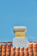 Brick chimney designed on slate roof of house building outside against blue sky background....