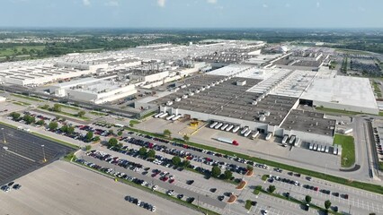 Car manufacturing plant in USA. Aerial pullback reveal shot of sprawling warehouse and facility. - Powered by Adobe