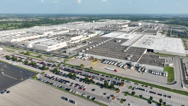 Car manufacturing plant in USA. Aerial pullback reveal shot of sprawling warehouse and facility.