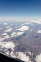 Beautiful view from the airplane window from above to the clouds, mountains, roads, rivers. Picturesque landscape from a helicopter window on a sunny day.
