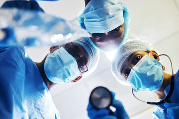 Surgery, medical and a team of doctors in an operating room at the hospital for a medical procedure from patient pov. Face, mask and teamwork with a group of medicine professionals in an operation - Powered by Adobe
