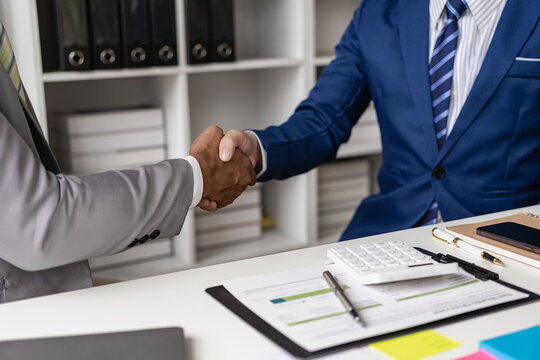 Two businessmen are agreeing on business together and shaking hands after successful negotiations. Shaking hands is a way of greeting or expressing congratulations. Close-up pictures