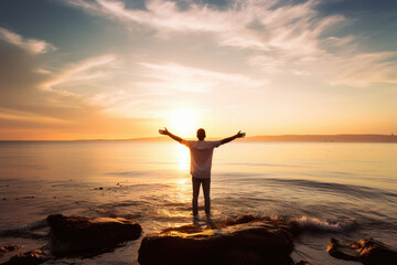 Young man standing with arms outstretched on the beach