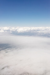 Beautiful view from the airplane window from above to the clouds, mountains, roads, rivers. Picturesque landscape from a helicopter window on a sunny day.