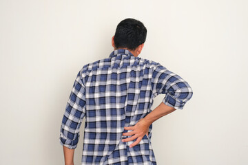 Rear view of adult man suffering back pain - obrazy, fototapety, plakaty