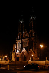 Fototapeta premium Roman Catholic cathedral, Gothic style architecture illuminated by night lanterns. Cathedral Basilica of the Assumption of the Blessed Virgin Mary. Białystok Cathedral, Bialystok, Poland 3 March 2021