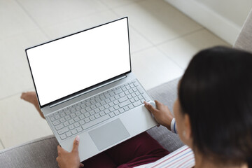 Happy biracial woman having laptop video call with copy space at home
